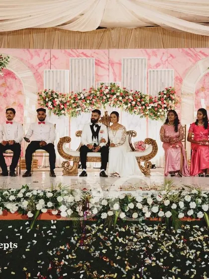 A beautiful moment from a wedding reception, showcasing the couple and their wedding party on a stage we designed. The pink marble backdrop and soft floral arches create a romantic and picture-perfect setting.