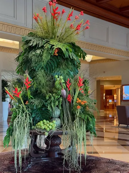 A well-curated foliage arrangement brings more than just beauty; it brings life and balance. Here, the structure is built from a variety of leaves, with fruits and bright red flowers adding color and interest.