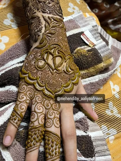 A close-up of the bride's personalized mehendi, featuring her and her partner's initials woven into a heart.