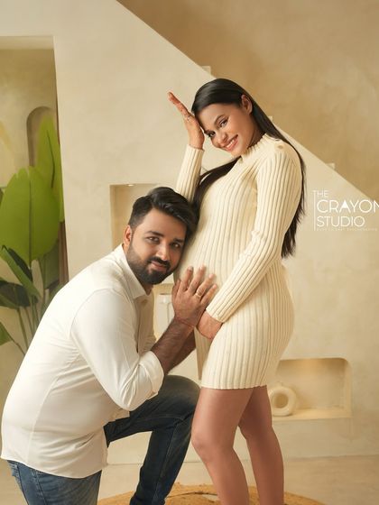 A playful and classic maternity pose. The dad to be listens to the baby bump, sharing a fun and loving moment with his partner.
