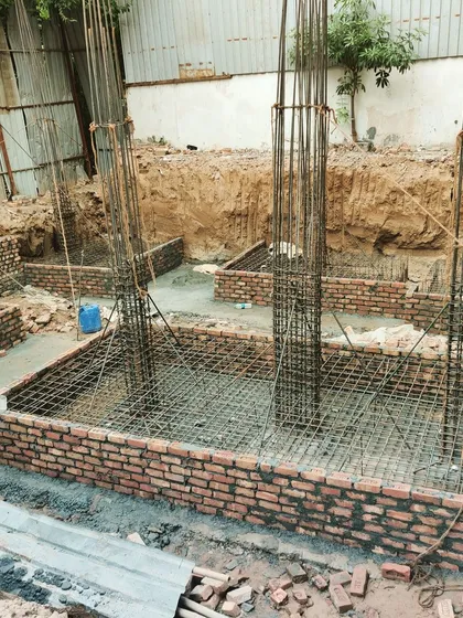 The foundation work for a new home in Gurugram, showing the steel columns rising from the footing cages. A strong and precisely laid foundation is non-negotiable for any project we undertake.