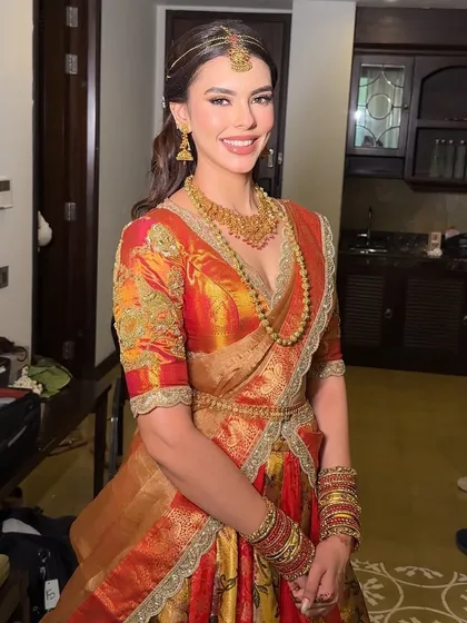 Stunning, elegant, and divine. Our South Indian bride shines in her rich Kanjeevaram half-saree with traditional gold temple jewelry and soft glam makeup.