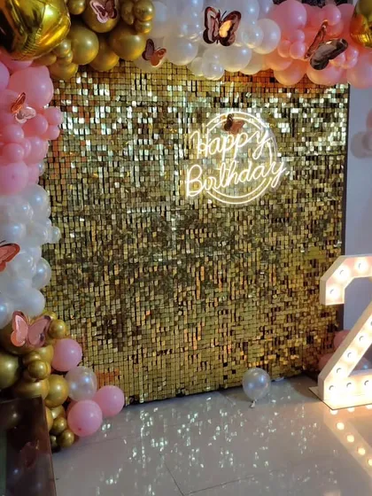 A pretty and playful second birthday setup. The gold sequin wall is paired with a pink and gold balloon arch, accented with butterfly details.