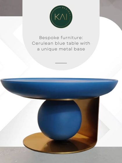 A sculptural side table in a vibrant cerulean blue, featuring a unique base that combines a sphere and a curved metal plate. This piece is designed to be a pop of color and a work of art in any contemporary space.