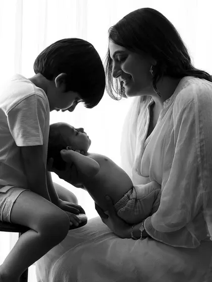 A beautiful black and white portrait showing a mother and older brother admiring the family's newest addition.