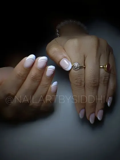 A modern take on the French manicure with abstract white swirls on a natural base.