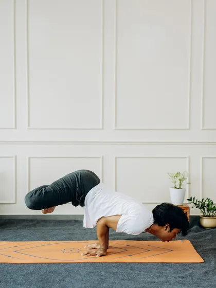 A side view of Bakasana, highlighting the importance of bringing the knees high onto the triceps and shifting the gaze forward to maintain balance. This is a pose of trust and strength.