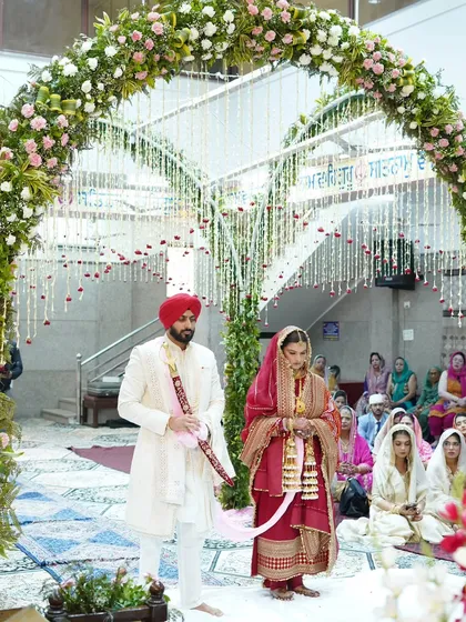 The solemnity of an Anand Karaj ceremony is truly special. Here, I framed the couple under the beautiful floral arch at the Gurudwara to capture the scale and serenity of this sacred Sikh wedding ritual.