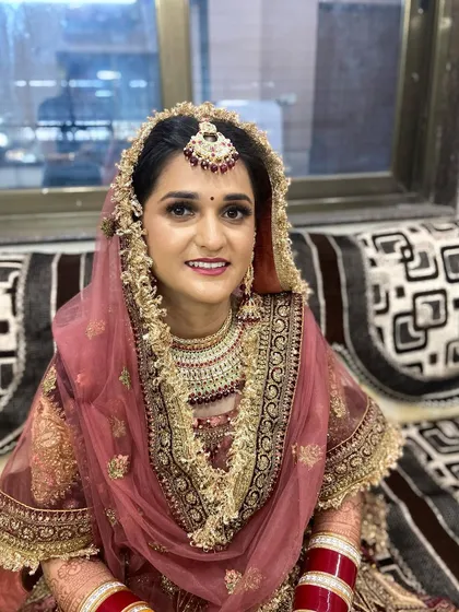A close-up of the Punjabi bride's makeup, highlighting the defined eyes and the traditional jewelry like the maang tikka and chooda.