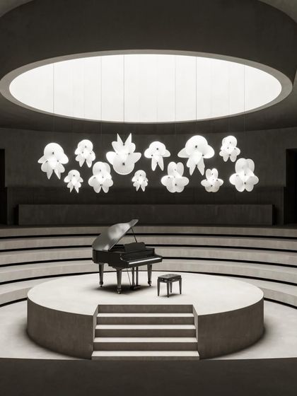 The large version of the Serpentine Light makes a grand statement in a concert hall setting, its multiple paper-like twists creating an elegant, floating sculpture above a grand piano.