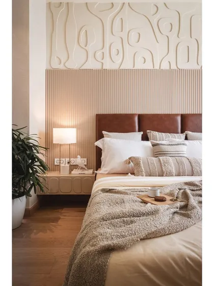 A closer view of the bed and custom headboard. The combination of the leather, fluted wood, and sculptural wall paneling creates a rich, tactile experience that feels both luxurious and comforting.