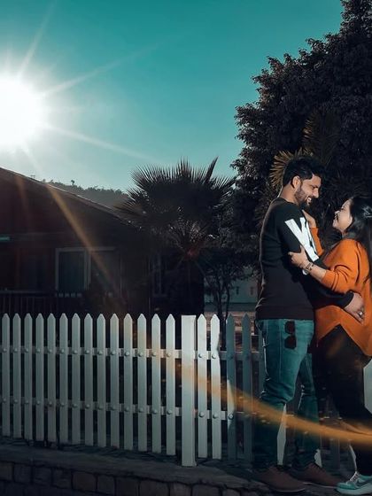A romantic shot of a couple in front of a wooden cabin, with a beautiful sun flare. The light leak effect adds a dreamy, vintage feel.