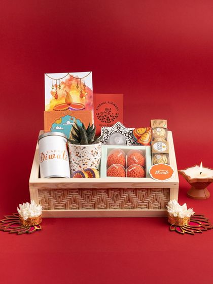 The complete Diwali hamper, presented with decorative diyas and flowers. It's a box full of light, sweetness, and good wishes for the festival.
