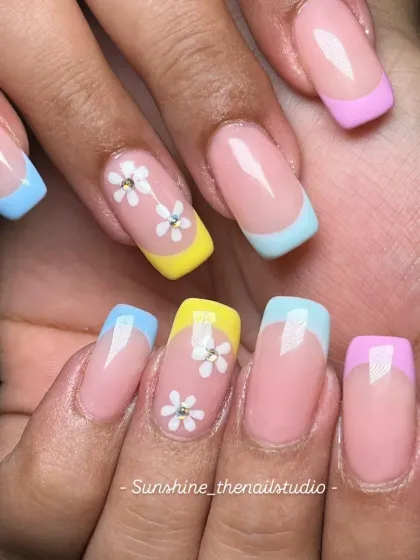 A playful and fresh take on the classic French manicure. This set uses square-shaped extensions with pastel rainbow tips in yellow, blue, and lilac, plus cute, hand-painted daisy accent nails.