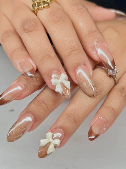 A sweet and sophisticated design with a brown chrome French tip and delicate 3D white bow accents.