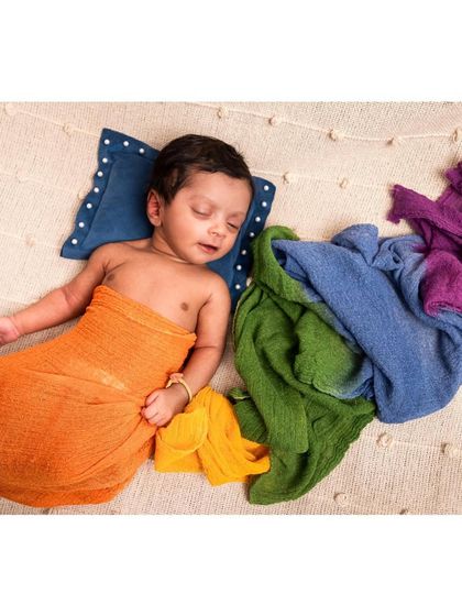 Another angle of our colorful wrap setup, this time showing the baby sleeping on their side. The vibrant colors of the fabric beautifully contrast with the neutral background.