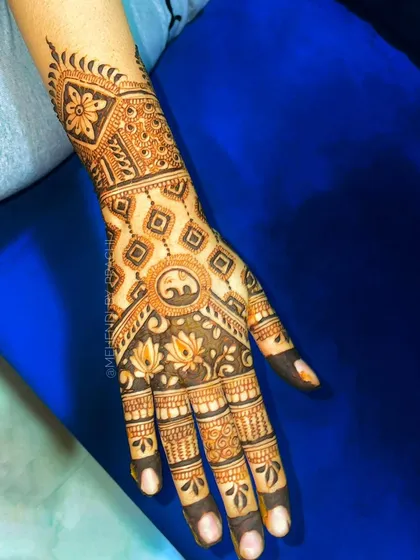 This back-hand design is a beautiful mix of geometric and floral patterns. It features a central elephant motif surrounded by lotus flowers and a diamond-patterned grid, covering the hand in elegant detail.