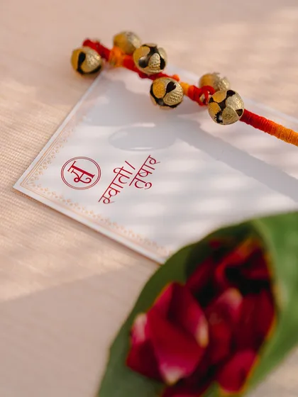 Custom wedding stationery for Swathi and Tushar, featuring their names in Hindi script, paired with ghungroo sticks and petals.