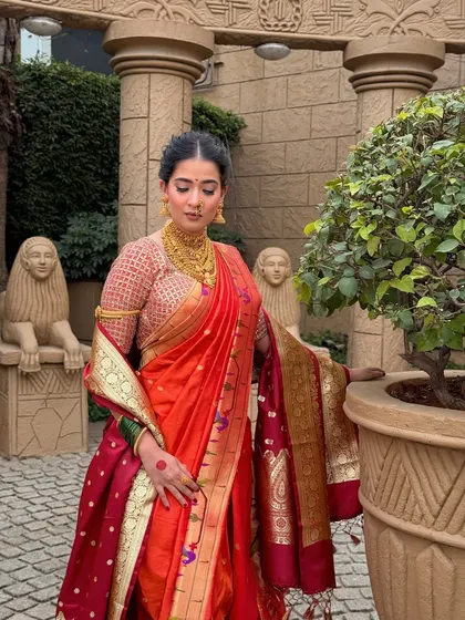 Posed against a classic architectural backdrop, this bride embodies royal elegance. Her makeup is flawless yet understated, allowing the rich colours of her saree to shine.