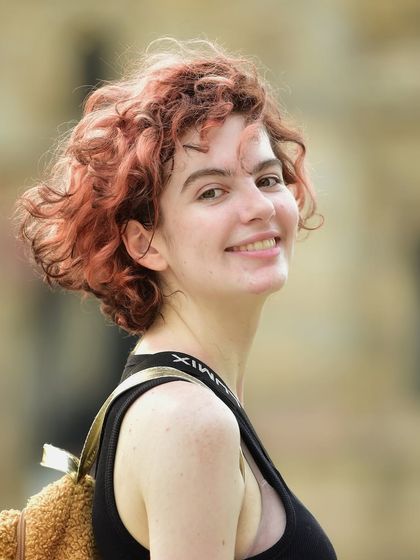 A bright and happy close up portrait. Her genuine smile and the warm, natural light make this a very cheerful and engaging shot.