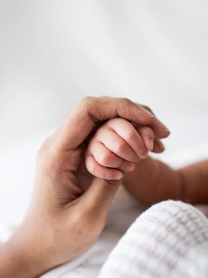 A newborn's hand grasping a parent's thumb. A simple, clean, and powerful image of connection.