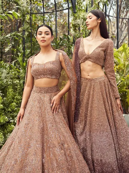 The rose gold lehengas from Varun Chakkilam's collection are designed for the woman who owns the room with quiet confidence. The full-sleeved blouse offers a chic, contemporary alternative.