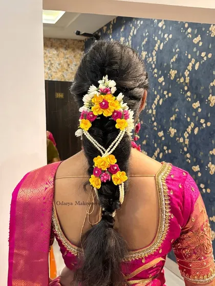 A vibrant and beautiful floral braid for a South Indian Haldi ceremony. The combination of yellow and pink flowers adds a festive touch to the traditional hairstyle.