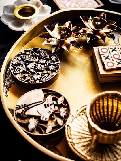 The beauty of gifting lies in the details. This arrangement showcases some of my favorite artisanal elements: hand-carved wooden stamps with traditional motifs, brass lotus candle holders, and a classic wooden game, all curated to create a welcome hamper that is both playful and elegant.