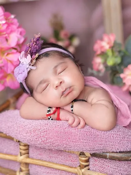 The 'potato sack' wrap pose is perfect for keeping newborns snug and sleepy. The pink tones are lovely for a baby girl.