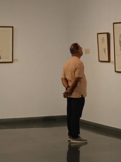 A visitor observes a series of framed drawings by Mohit Mahato, his shadow cast on the wall beside him.