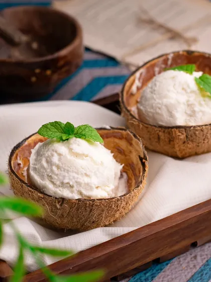 A scoop of coconut ice cream served in a natural coconut shell. This creative presentation is both rustic and refreshing.