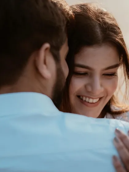 A beautiful over-the-shoulder shot focusing on the bride's joyful expression as she embraces her partner. This highlights pure, candid emotion.