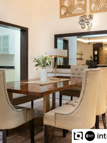 An elegant dining room designed for formal gatherings. The high-back upholstered chairs with nailhead trim add a touch of classic sophistication, while the large mirror reflects light and makes the space feel more expansive.
