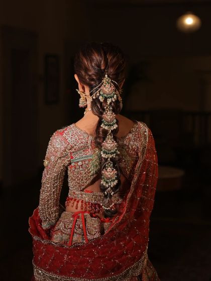 The back of the bridal look is just as important. Here, we've styled the hair with an elaborate braid accessory that complements the heavy embroidery of the lehenga.