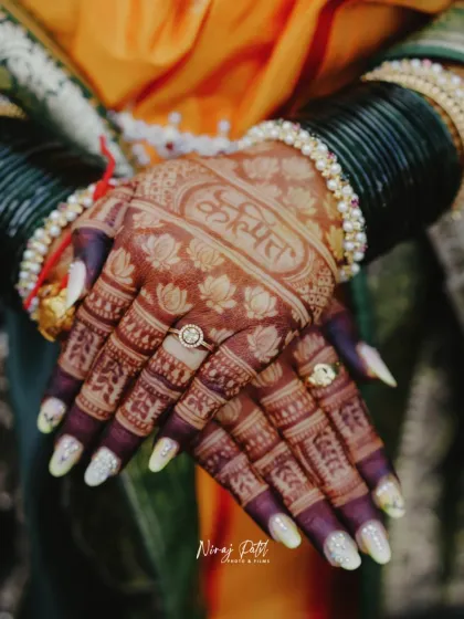 A beautiful shot of the developed henna stain, with the groom's name elegantly scripted on the bride's hand, adorned with traditional Maharashtrian green bangles.
