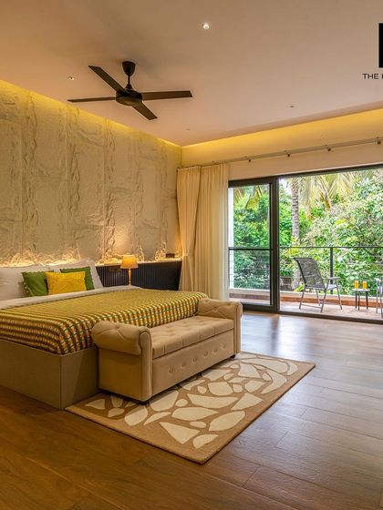 A spacious bedroom in the villa opens onto a private balcony, offering guests a personal space to enjoy the tranquil views. The design combines natural textures with modern comforts.