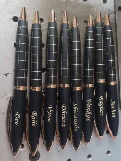 A set of premium checkered pens, each engraved with a different name.