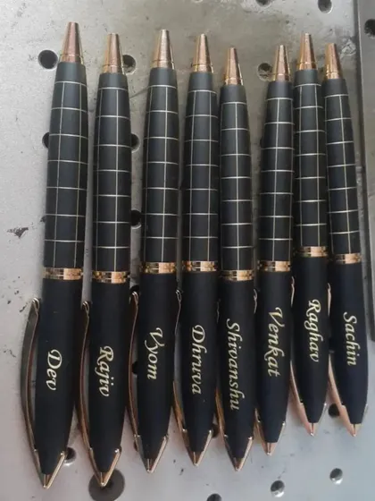 A set of personalized pens with a checkered design, each engraved with a different name. The rose gold accents give them a very modern look.