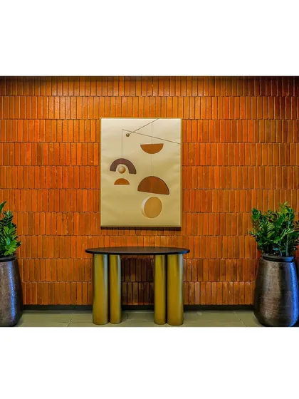 A simple console table stands against a warm, terracotta-colored brick wall, accented by a modern art piece. This vignette adds a touch of artistic flair to the clubhouse common area.