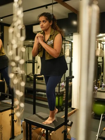 A client demonstrates a challenging single leg exercise on the Pilates Chair. This move requires core strength, balance, and alignment, activating stabilizer muscles to improve neuromuscular control and joint strength.
