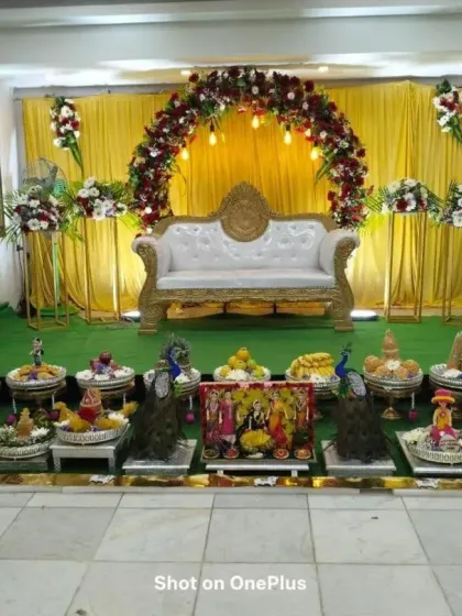 A full view of the stage and Seer Thattu decorations from a different angle. The combination of the floral backdrop and the traditional offerings makes for a complete and beautiful setup.