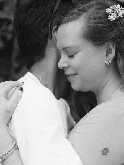 A quiet, intimate moment captured in timeless black and white. The bride's gentle smile and the couple's close embrace speak volumes about their deep connection.