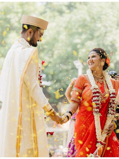 Surrounded by a shower of petals, Vicky and Aishwarya hold hands and smile. This shot is full of movement, color, and joy, a perfect snapshot of their celebration.