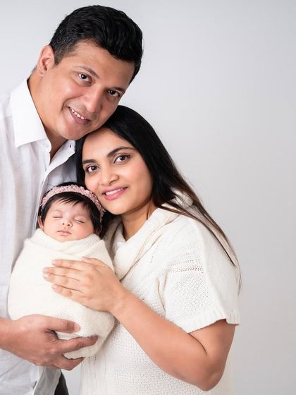 A classic family photo with both parents looking at the camera. This is a timeless shot that every family treasures, a beautiful record of this special time in their lives.