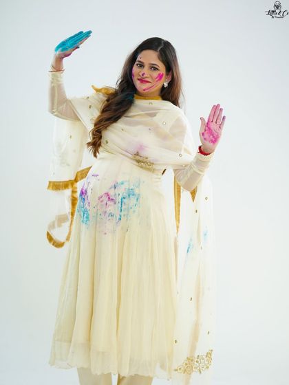 A solo shot of the mother-to-be celebrating with color. Her happy expression and waving hands create a dynamic and joyful image from our unique Holi-themed shoot.