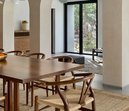 The use of natural materials like wood and woven jute brings an organic, tactile quality to this dining area. The open archways provide a fluid connection to the adjacent living spaces and the views beyond.