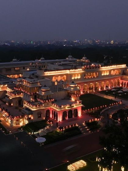 A beautiful dusk shot of a palace hotel in Jaipur. The warm lights of the property stand out against the evening sky, creating an inviting and luxurious image for potential visitors.