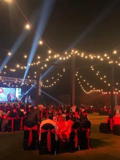 Let's get the party started with a sangeet night to remember. We transformed this outdoor lawn in Lonavala with dramatic stage lighting, a large LED screen for performances, and cozy string lights to create a festive atmosphere perfect for an evening of *nacho tappo*.