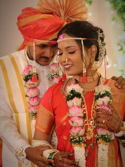 A romantic photo of the bride and groom. Her red Nauvari and his traditional attire create a stunning visual, and her makeup is the perfect finishing touch.