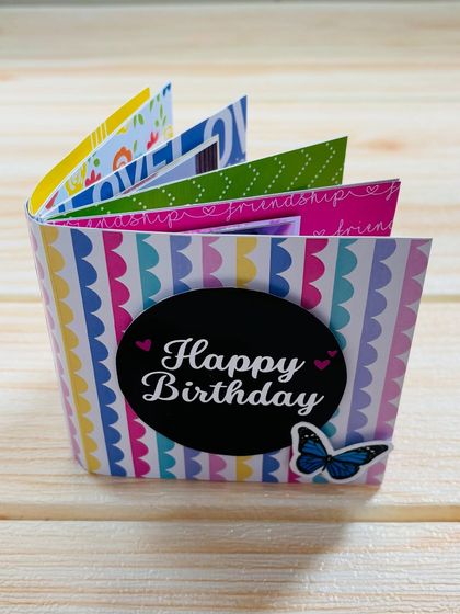 This is a keepsake mini album, standing up to show its accordion-style pages. It's perfect for a birthday and holds 5 photos and 5 messages.